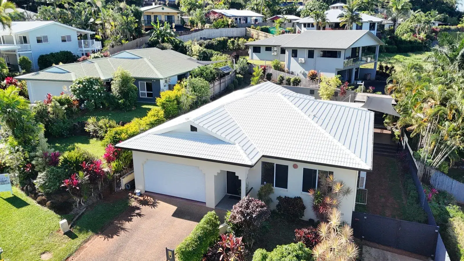 Aerial view of a freshly restored white tile roof on a Cairns home, surrounded by tropical gardens